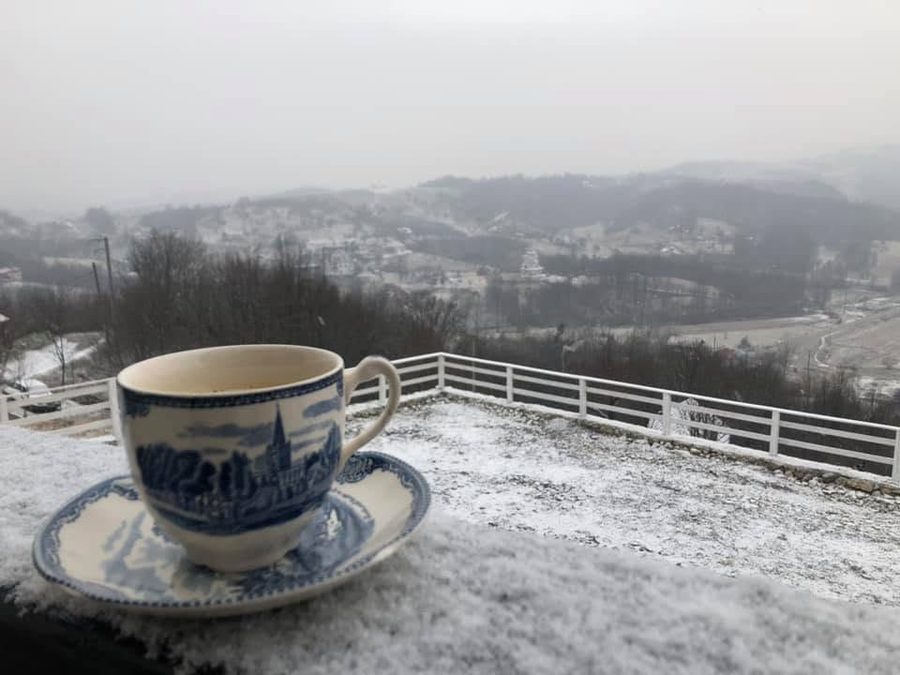 Ceașcă de cafea pe balustrada acoperită de zăpadă