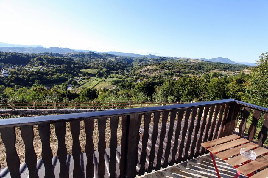 Panorama de pe balcon: dealuri împădurite și munți la orizont